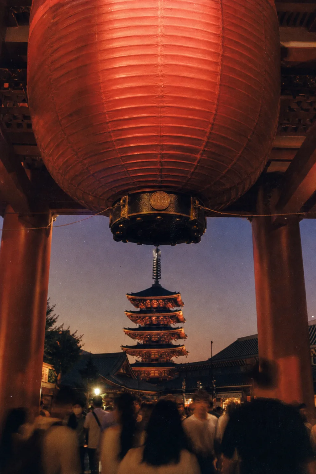 A huge red paper lantern hanging in a temple gate at dusk